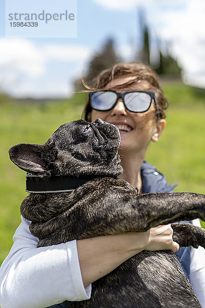 Glückliche Frau trägt ihre faule Bulldogge