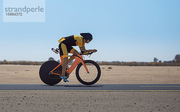 Entschlossener Radfahrer fährt Fahrrad auf der Straße in der Wüste in Dubai  Vereinigte Arabische Emirate