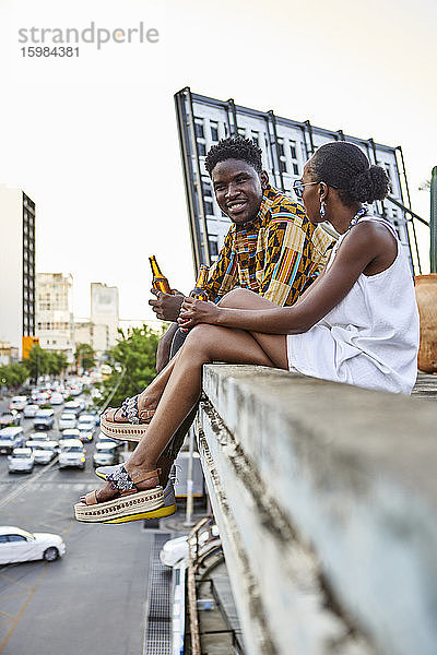 Paar sitzt auf einer Dachterrasse in der Stadt und trinkt Bier  Maputo  Mosambik