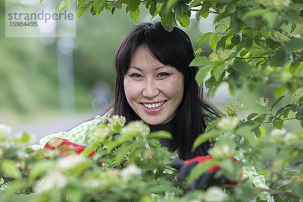 Lächelnde Frau schaut in die Kamera im städtischen Garten