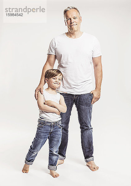 Porträt eines Vaters und seines kleinen Sohnes vor weißem Hintergrund