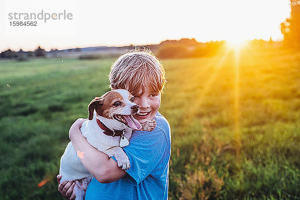 Fröhlicher Junge mit Hund auf einem Feld an einem sonnigen Tag  Polen