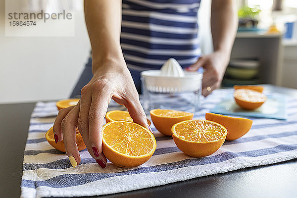 Frau  die frischen Orangensaft zubereitet  nimmt eine in Scheiben geschnittene Orange
