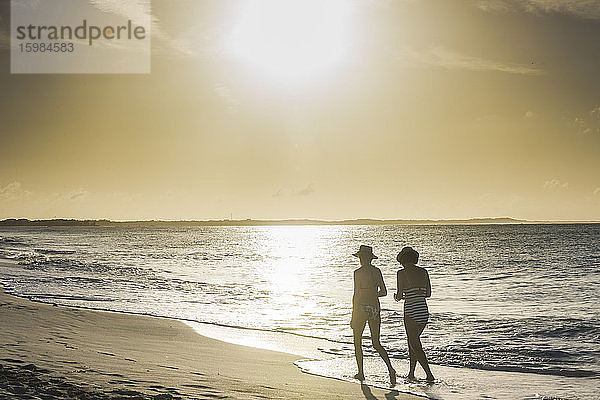 Rückansicht von Freundinnen beim Spaziergang am Strand von Grace Bay bei Sonnenuntergang  Providenciales  Turks- und Caicosinseln