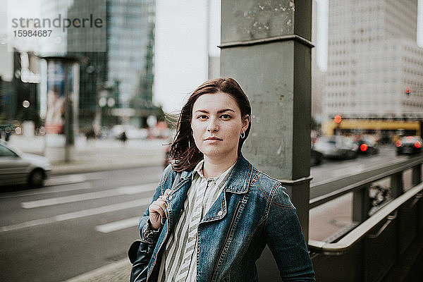 Deutschland  Berlin  Porträt einer jungen Frau auf dem Bürgersteig