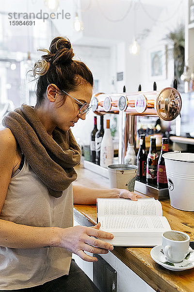 Frau liest Buch in einem Café