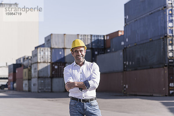 Porträt eines selbstbewussten Geschäftsmannes mit Schutzhelm vor einem Frachtcontainer