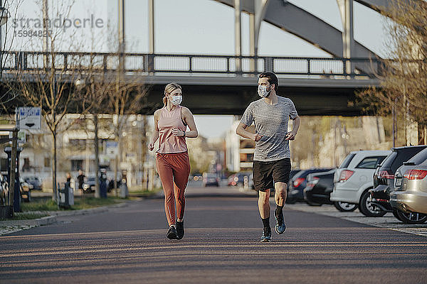 Junges Paar joggt während des Coronavirus auf der Straße in der Stadt