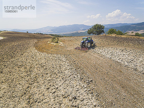 Traktor pflügt auf einem Bauernhof gegen den Himmel in der Basilicata  Italien
