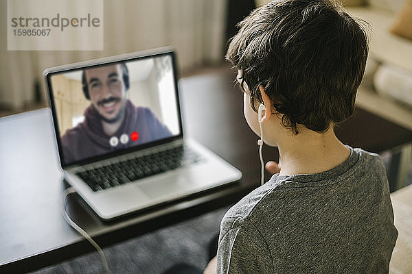 Kleiner Junge benutzt einen Laptop für einen Videochat mit seinem Vater