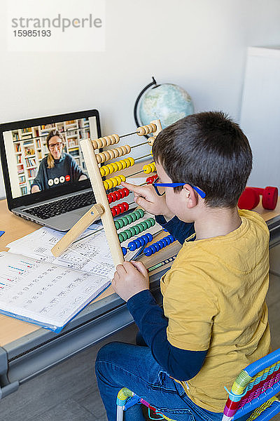 Grundschüler benutzt Abakus mit Lehrer per Videoanruf während des Hausunterrichts
