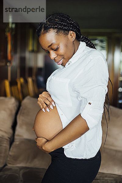 Porträt einer schwangeren jungen Frau  die ihren Bauch berührt