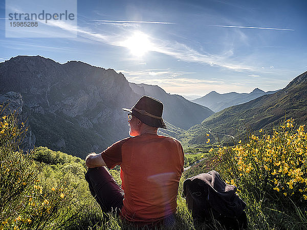 Rückansicht eines älteren Mannes  der auf einem Berg gegen den Himmel sitzt  Alto de La Farrapona  Asturien  Spanien