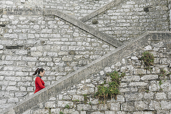 Seitenansicht einer lächelnden Frau  die eine Treppe hinaufgeht  Itzurun  Zumaia  Spanisches Baskenland  Spanien