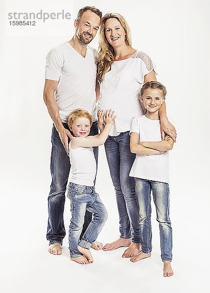 Familienporträt mit schwangerer Mutter und zwei Kindern  die vor einem weißen Hintergrund stehen