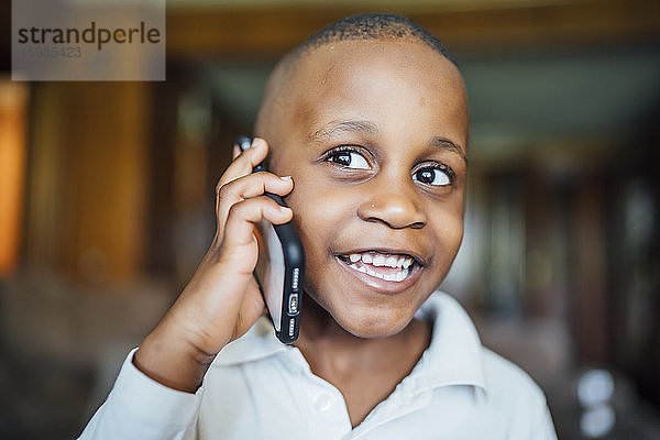 Porträt eines glücklichen kleinen Jungen am Telefon