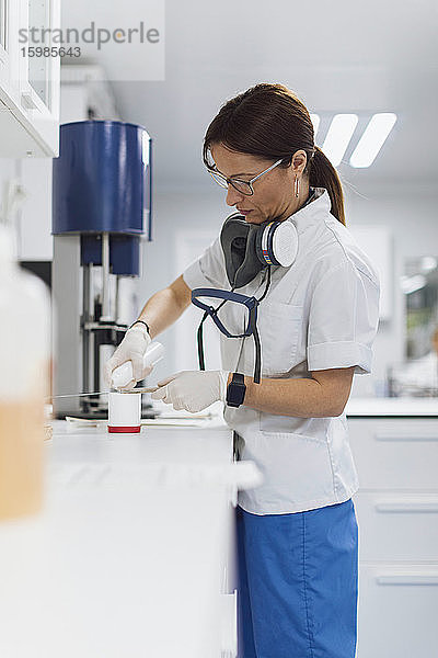 Selbstbewusste Mitarbeiterin des Gesundheitswesens gießt Medikamente in einen Behälter im Labor