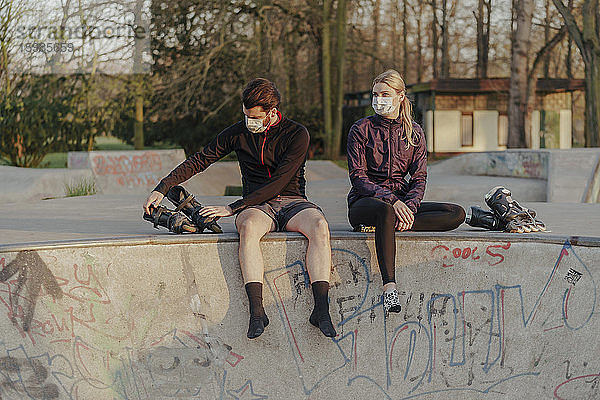 Junges Paar sitzt mit Inline-Skates im Skateboard-Park