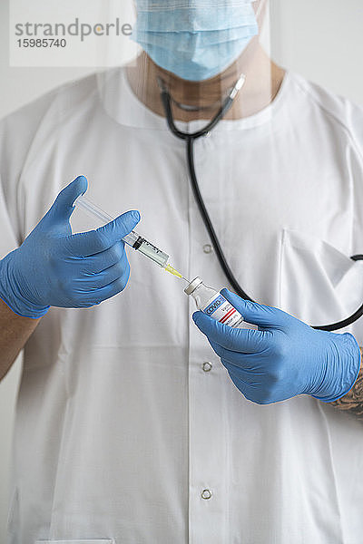 Mann in Schutzkleidung bei der Vorbereitung der Covid-19-Impfung
