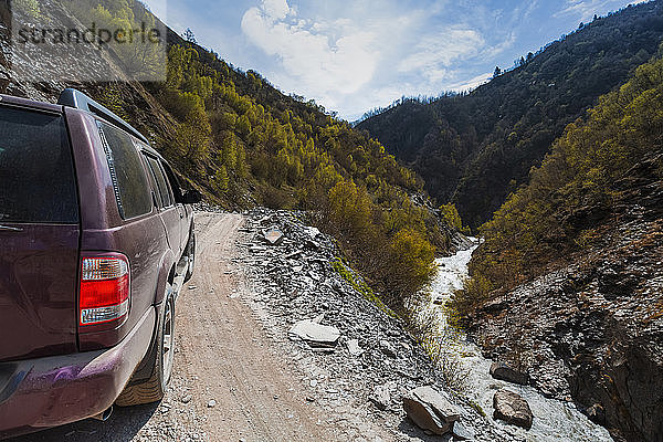 Georgien  Swanetien  Ushguli  4x4 Auto auf der Bergstraße mit Blick auf den Fluss  der durch das bewaldete Tal fließt