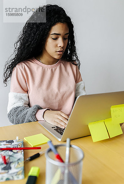 Junge Frau arbeitet von zu Hause aus am Laptop