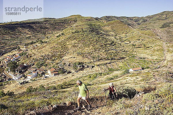 Spanien  Kanarische Inseln  La Gomera  Zwei Wanderer beim Aufstieg zum Tafelberg mit Dorf im Hintergrund