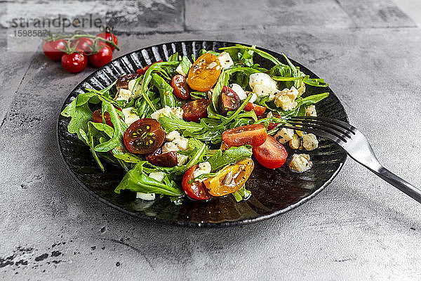 Teller mit vegetarischem Low-Carb-Salat mit Rucola  Tomaten  Nüssen und Mozzarella