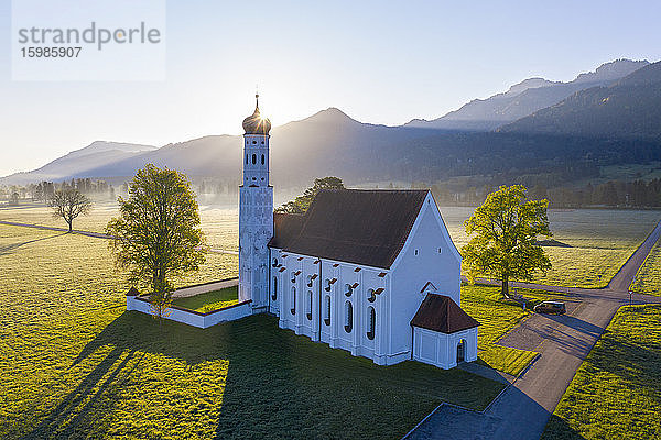 Deutschland  Bayern  Schwangau  Drohnenansicht der Kirche St. Coloman bei Sonnenaufgang