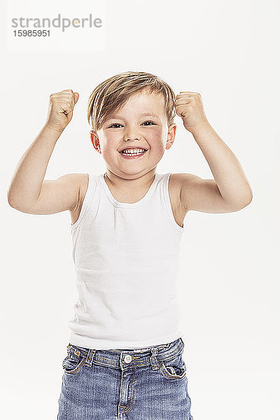Porträt eines kleinen Jungen  der die Fäuste ballt  vor einem weißen Hintergrund