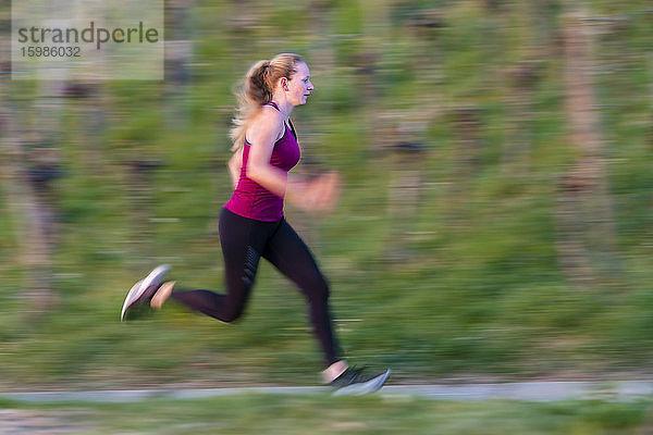 Seitenansicht in voller Länge einer jungen Frau  die in einem Weinberg sprintet