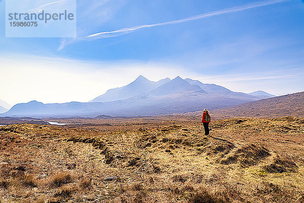 Ältere Frau  die auf dem Land steht  mit den Cuillin-Bergen im Hintergrund  Isle of Skye  Highlands  Schottland  UK