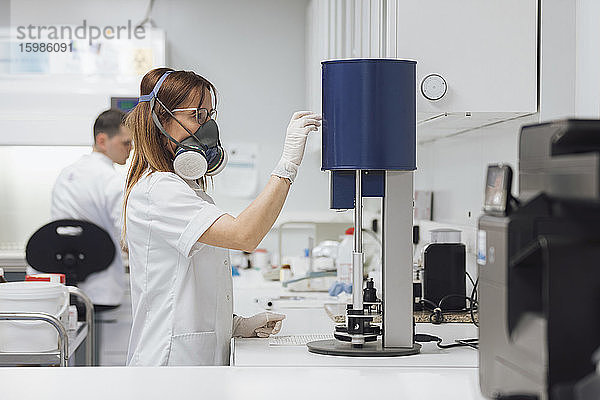 Weiblicher Techniker benutzt medizinische Geräte  während ein männlicher Kollege im Labor arbeitet