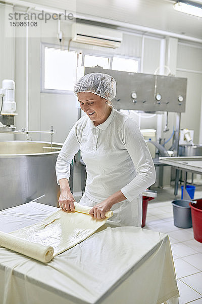 Käseproduktion  Arbeiterin rollt Käse  gerollter Schichtkäse