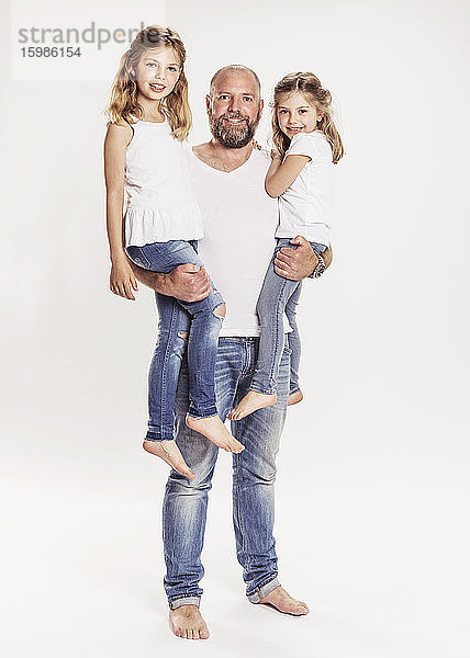 Porträt eines glücklichen Mannes mit seinen beiden Töchtern vor einem weißen Hintergrund