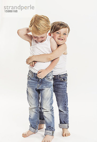 Porträt eines kleinen Jungen  der einen anderen kleinen Jungen umarmt  vor einem weißen Hintergrund