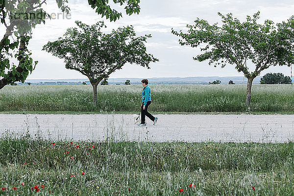 Ältere Frau geht mit ihrem Hund auf dem Lande spazieren
