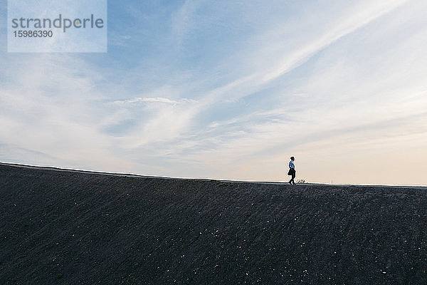 Männlicher Unternehmer geht auf einem Hügel gegen den Himmel bei Sonnenuntergang