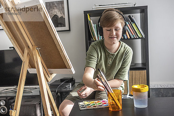 Junge malt an der Staffelei und hört Musik