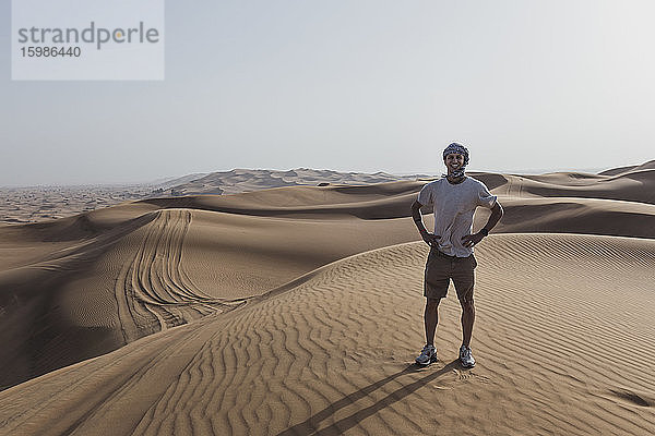 Glücklicher männlicher Tourist  der auf Sanddünen in der Wüste von Dubai  Vereinigte Arabische Emirate  steht