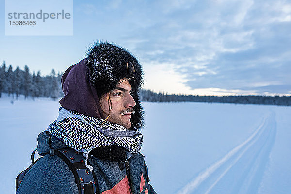 Porträt eines Mannes in Winterlandschaft mit gefrorenem Schnurrbart  Ounasjaervi  Enontekioe  Finnland