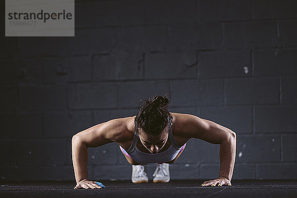 Frau übt Liegestütz im Fitnessstudio