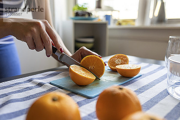 Frau schneidet frische Orangen für frisch gepressten Orangensaft