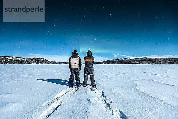 Schneeschuhwanderer stehen in der Winterlandschaft und beobachten Nordlichter über Ropijarvi  Ropinsalmi  Enontekioe  Finnland