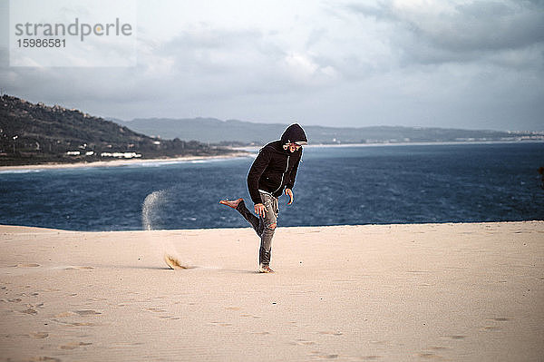 Junger Mann springt am Strand gegen den Himmel in Tarifa  Spanien