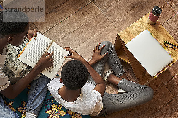 Draufsicht auf ein junges Paar  das zu Hause gemeinsam ein Buch liest