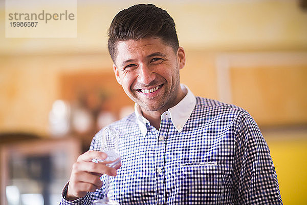 Deutschland  Niedersachsen  Hannover  Porträt eines gut aussehenden Mannes  der mit einem Weinglas in der Hand in die Kamera lächelt