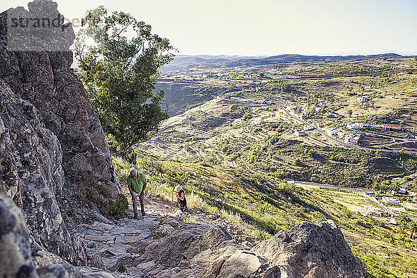 Spanien  Kanarische Inseln  La Gomera  Zwei Wanderer beim Aufstieg zum Tafelberg mit Bergdorf im Hintergrund