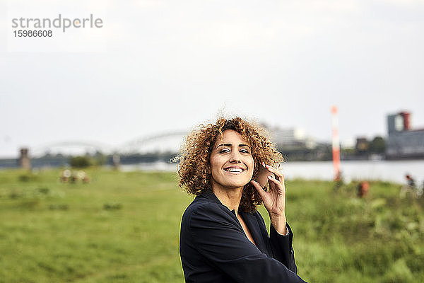 Geschäftsfrau mit Smartphone am Flussufer in Köln  Deutschland