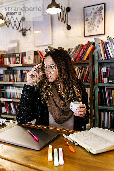 Frau schreibt in einem Café in ein Notizbuch