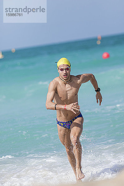 Männlicher Schwimmer  der am Strand von Dubai  Vereinigte Arabische Emirate  ans Ufer läuft